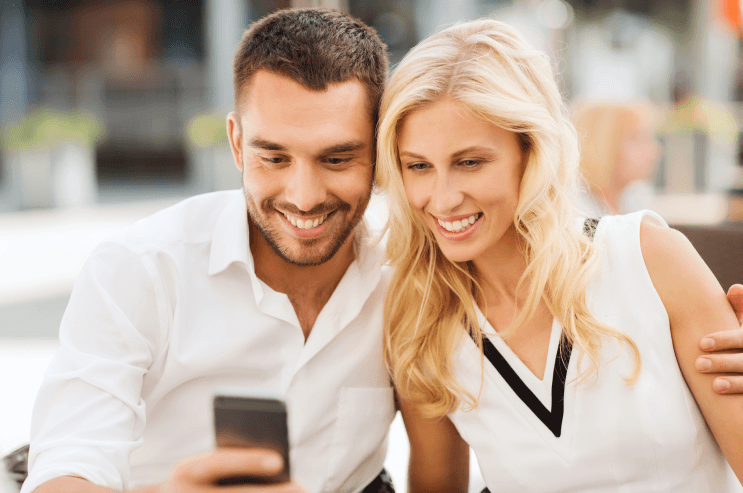 love_date_technology_people_relations_concept_smiling_happy_couple_with_smatphone_city_street_cafe_1_36a52abb26